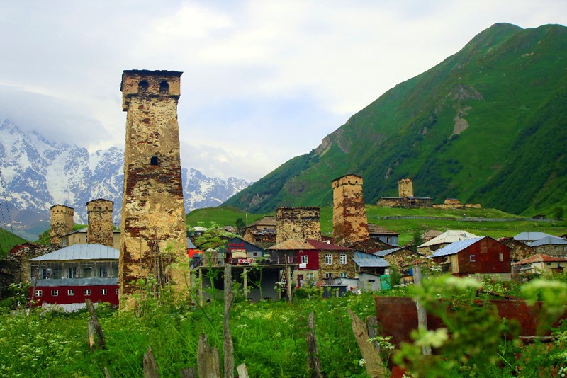 Obzor nad Usghuli rámují bílé vrcholky hlavního kavkazského hřebene